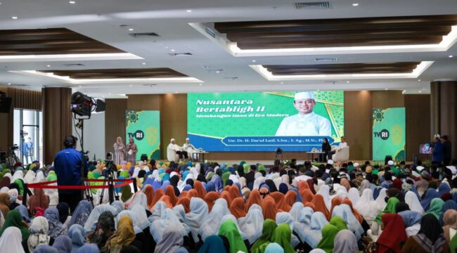 Foto: Ribuan peserta memadati kegiatan Nusantara Bertabligh II di Ibu Kota Nusantara. Acara yang digelar di sebuah aula besar ini menampilkan seorang penceramah di atas panggung serta tayangan visual bertema keagamaan di layar utama, dengan tim produksi TVRI turut melakukan peliputan. (Dok. Humas OIKN)